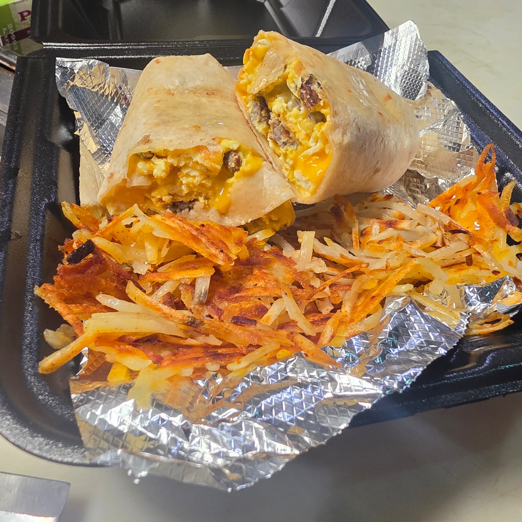 Breakfast burrito with eggs, cheese and sausage served with crispy hash browns