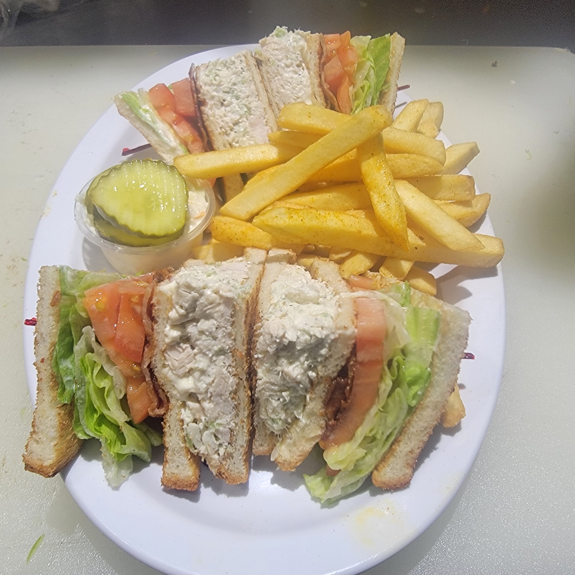 Chicken salad club sandwich with fries and pickle
